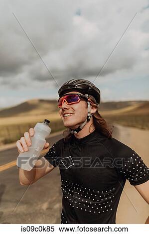 Young male cyclist holding water bottle on rural road, Exeter, California, USA View Large Photo Image Stock Photography - Young male cyclist holding water bottle on rural road, Exeter, California, USA. Fotosearch