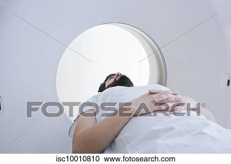 Stock Image - Young male patient having a CT scan in radiology department. Fotosearch