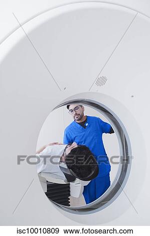 Stock Photo - Young male radiographer operating operating CT scanner in radiology department. Fotosearch