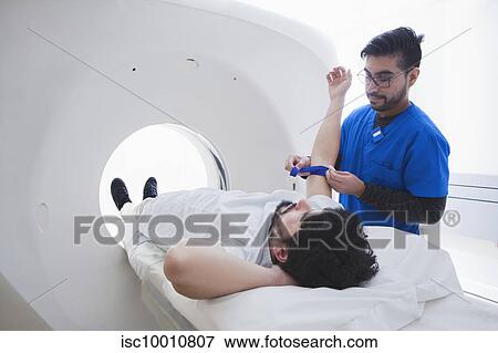 Young male radiographer preparing male patient for CT scan in radiology department View Large Photo Image Stock Photo - Young male radiographer preparing male patient for CT scan in radiology department. Fotosearch