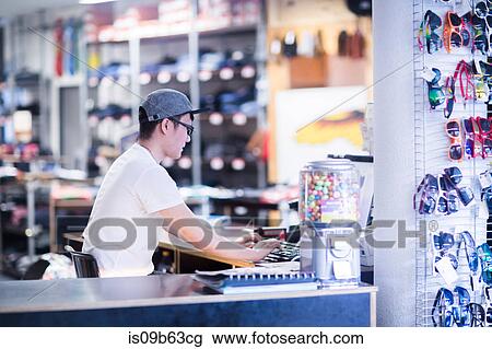 Young male sales assistant typing on computer keyboard at skateboard shop counter View Large Photo Image Stock Image - Young male sales assistant typing on computer keyboard at skateboard shop counter. Fotosearch