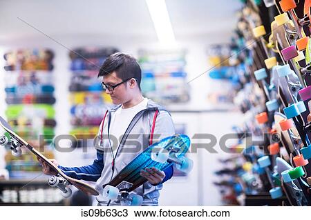 Young male skateboarder looking at skateboards in skateboard shop View Large Photo Image Stock Image - Young male skateboarder looking at skateboards in skateboard shop. Fotosearch