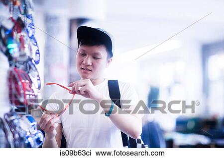 Young male skateboarder looking at sunglasses in skateboard shop View Large Photo Image Stock Image - Young male skateboarder looking at sunglasses in skateboard shop. Fotosearch