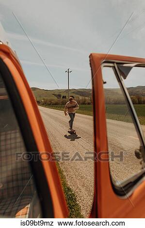 Young male skateboarder skateboarding along rural road next to recreational vehicle, Jalama, California, USA View Large Photo Image Stock Photo - Young male skateboarder skateboarding along rural road next to recreational vehicle, Jalama, California, USA. Fotosearch