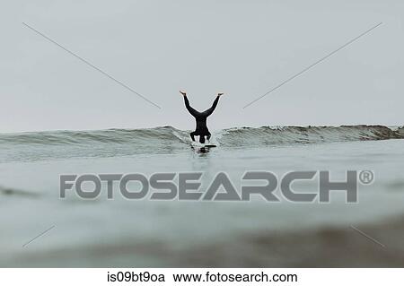 Young male surfer doing headstand on surfboard in misty sea, Ventura, California, USA View Large Photo Image Stock Image - Young male surfer doing headstand on surfboard in misty sea, Ventura, California, USA. Fotosearch