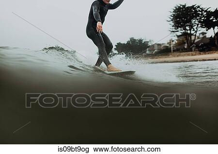 Stock Image - Young male surfer surfing on calm sea, Ventura, California, USA. Fotosearch
