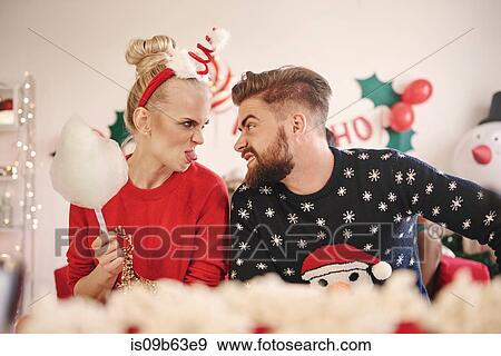 Stock Photo - Young man and woman making faces at each other at christmas party. Fotosearch