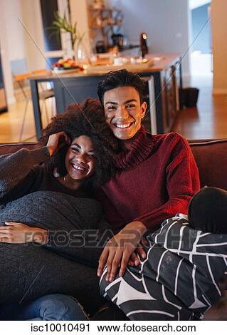 Young man and young female girlfriend smiling while watching tv on living room sofa View Large Photo Image Stock Image - Young man and young female girlfriend smiling while watching tv on living room sofa. Fotosearch