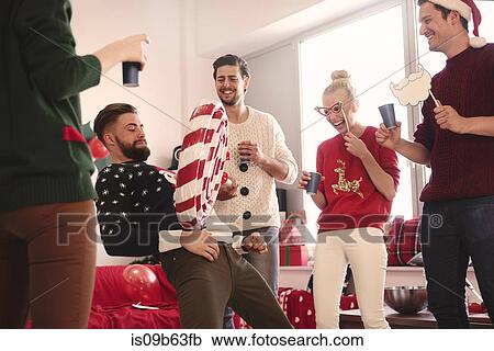 Stock Image - Young man balancing giant lollipop on his stomach at christmas party. Fotosearch