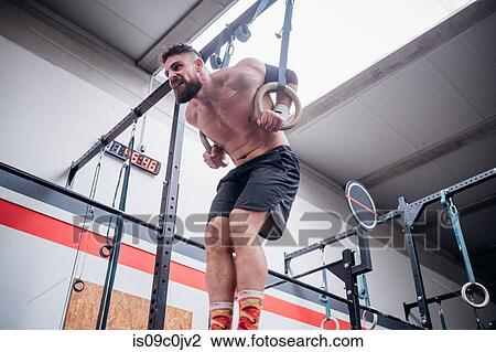 Young man balancing on gymnastic rings in gym View Large Photo Image Stock Image - Young man balancing on gymnastic rings in gym. Fotosearch