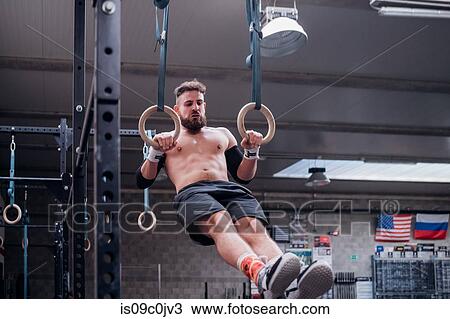 Young man balancing on gymnastic rings in gym View Large Photo Image Stock Image - Young man balancing on gymnastic rings in gym. Fotosearch