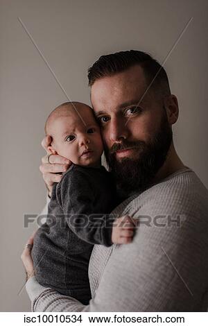 Young man carrying baby son in arms, portrait View Large Photo Image Picture - Young man carrying baby son in arms, portrait. Fotosearch