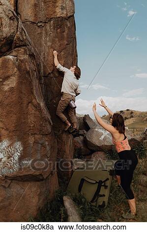 Young man climbing up rock face, girlfriend watching, Exeter, California, USA View Large Photo Image Stock Image - Young man climbing up rock face, girlfriend watching, Exeter, California, USA. Fotosearch