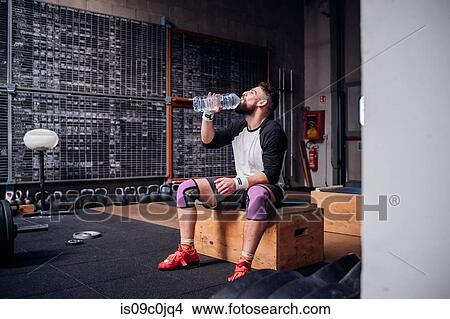 Young man drinking water in gym View Large Photo Image Picture - Young man drinking water in gym. Fotosearch