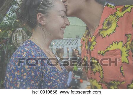 Young man giving girlfriend a kiss on the forehead at community garden party, cropped side view View Large Photo Image Stock Photograph - Young man giving girlfriend a kiss on the forehead at community garden party, cropped side view. Fotosearch