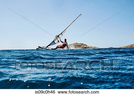 Young man leaning back windsurfing ocean waves, surface level view, Limnos, Khios, Greece View Large Photo Image Stock Photograph - Young man leaning back windsurfing ocean waves, surface level view, Limnos, Khios, Greece. Fotosearch