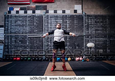 Young man lifting weight bar in gym View Large Photo Image Stock Photo - Young man lifting weight bar in gym. Fotosearch