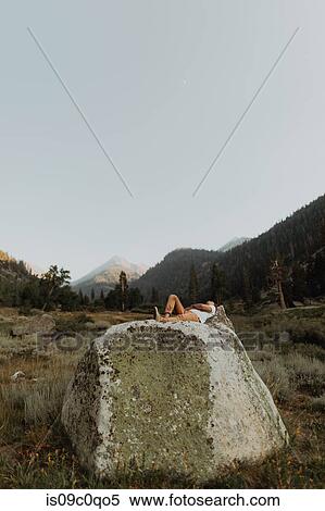 Stock Photography - Young man lying on boulder in rural valley, Mineral King, California, USA. Fotosearch
