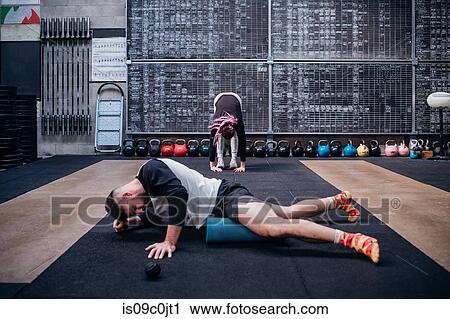 Young man massaging thigh with foam roller in gym View Large Photo Image Stock Image - Young man massaging thigh with foam roller in gym. Fotosearch