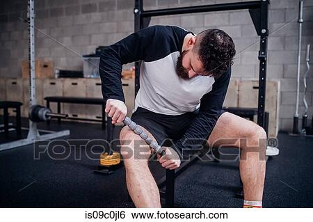 Young man massaging thigh with muscle roller stick in gym View Large Photo Image Stock Photograph - Young man massaging thigh with muscle roller stick in gym. Fotosearch