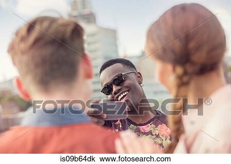 Young man photographing friends at roof party in London, UK View Large Photo Image Stock Image - Young man photographing friends at roof party in London, UK. Fotosearch