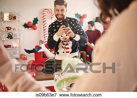 Young man photographing woman preparing candyfloss at christmas party View Large Photo Image Stock Photo - Young man photographing woman preparing candyfloss at christmas party. Fotosearch