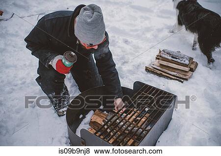 Young man preparing to light barbecue fire in snow View Large Photo Image Stock Photo - Young man preparing to light barbecue fire in snow. Fotosearch