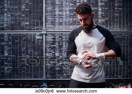 Young man putting on handwrap in gym View Large Photo Image Stock Photograph - Young man putting on handwrap in gym. Fotosearch