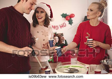 Stock Photo - Young man serving punch to friends at christmas party. Fotosearch