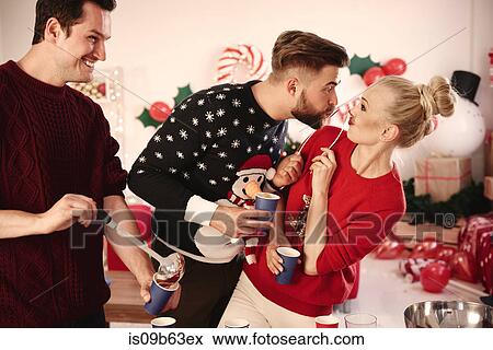 Stock Photo - Young man serving punch to friends at christmas party. Fotosearch