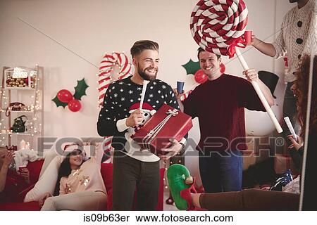 Stock Photography - Young man singing with pretend microphone at christmas party. Fotosearch