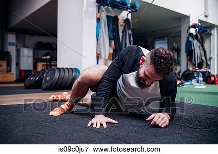 Stock Photo - Young man stretching legs in gym. Fotosearch