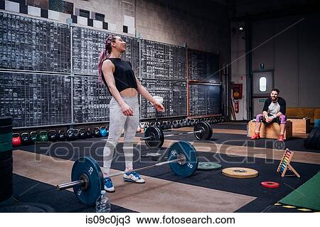 Young man watching woman preparing to lift barbell in gym View Large Photo Image Stock Image - Young man watching woman preparing to lift barbell in gym. Fotosearch