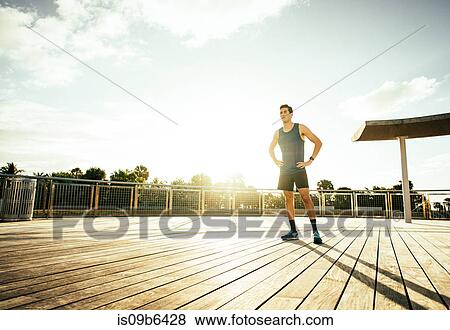 Young man wearing sports clothing, standing outdoors, hands on hips View Large Photo Image Stock Photo - Young man wearing sports clothing, standing outdoors, hands on hips. Fotosearch