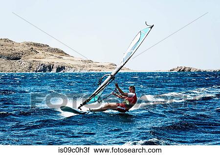 Stock Image - Young man windsurfing ocean waves, Limnos, Khios, Greece. Fotosearch