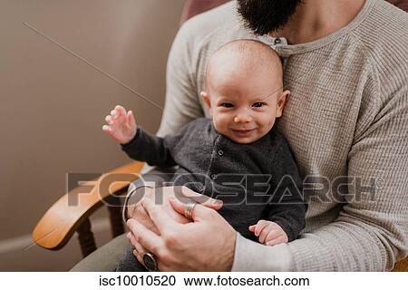 Young man with baby son on lap, cropped portrait View Large Photo Image Stock Image - Young man with baby son on lap, cropped portrait. Fotosearch