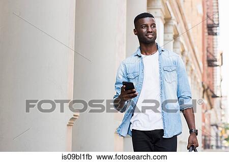 Young man with hand luggage holding cellphone in streets of New York, US View Large Photo Image Stock Image - Young man with hand luggage holding cellphone in streets of New York, US. Fotosearch