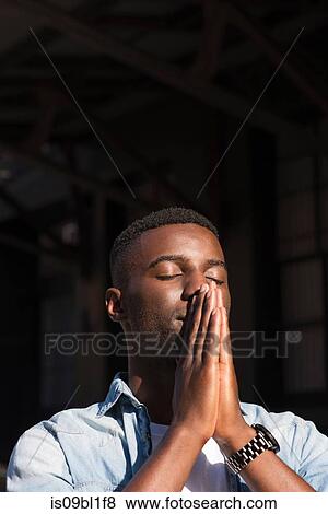 Young man with palms together on face View Large Photo Image Stock Photo - Young man with palms together on face. Fotosearch