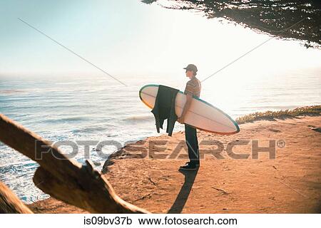 Young man with surfboard on beach, Morro Bay, California, United States View Large Photo Image Stock Image - Young man with surfboard on beach, Morro Bay, California, United States. Fotosearch