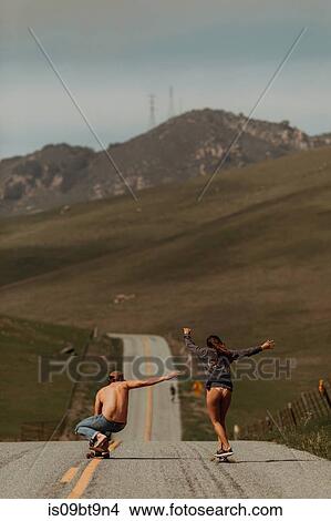 Young skateboarder couple skateboarding down rural road, rear view, Jalama, California, USA View Large Photo Image Picture - Young skateboarder couple skateboarding down rural road, rear view, Jalama, California, USA. Fotosearch