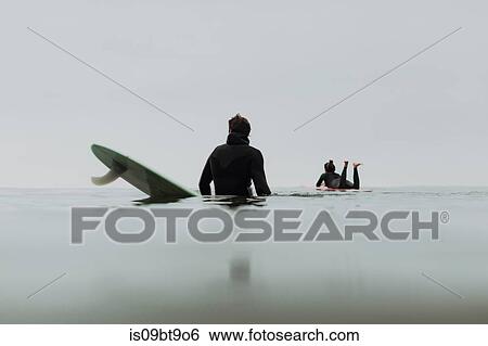 Stock Photograph - Young surfer couple on surfboards in calm misty sea, Ventura, California, USA. Fotosearch
