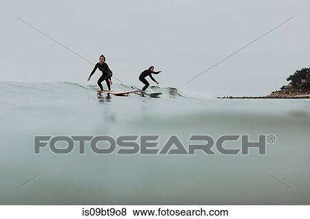 Stock Photo - Young surfer couple surfing on calm misty sea, Ventura, California, USA. Fotosearch