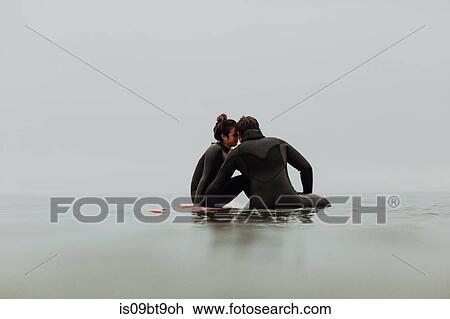Young surfing couple sitting on surfboards in calm misty sea, Ventura, California, USA View Large Photo Image Stock Image - Young surfing couple sitting on surfboards in calm misty sea, Ventura, California, USA. Fotosearch