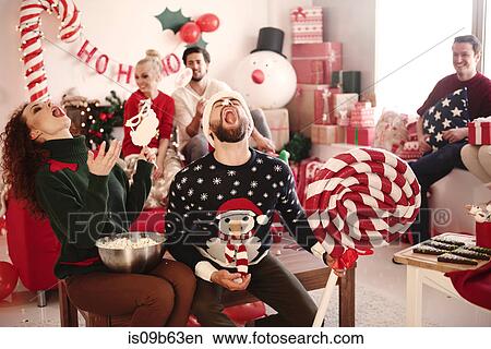 Young woman and man catching popcorn in open mouths at christmas party View Large Photo Image Picture - Young woman and man catching popcorn in open mouths at christmas party. Fotosearch