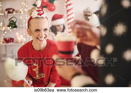 Stock Image - Young woman and man with candyfloss and popcorn at christmas party. Fotosearch