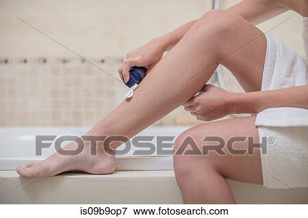 Stock Photo - Young woman applying shaving foam to leg in bathroom, cropped. Fotosearch