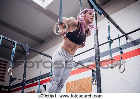 Young woman balancing on gymnastic rings in gym View Large Photo Image Stock Image - Young woman balancing on gymnastic rings in gym. Fotosearch
