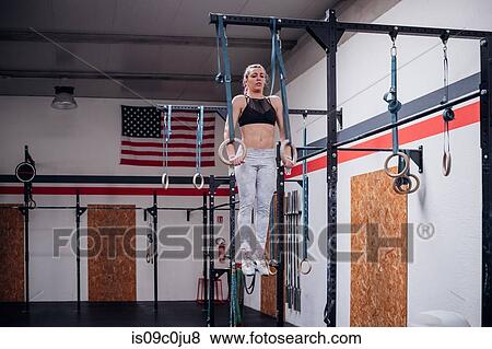 Stock Photo - Young woman balancing on gymnastic rings in gym. Fotosearch