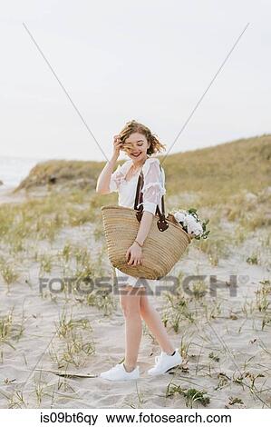 Young woman carrying shoulder bag with flowers on coastal dunes, Menemsha, Martha's Vineyard, Massachusetts, USA View Large Photo Image Stock Photo - Young woman carrying shoulder bag with flowers on coastal dunes, Menemsha, Martha's Vineyard, Massachusetts, USA. Fotosearch