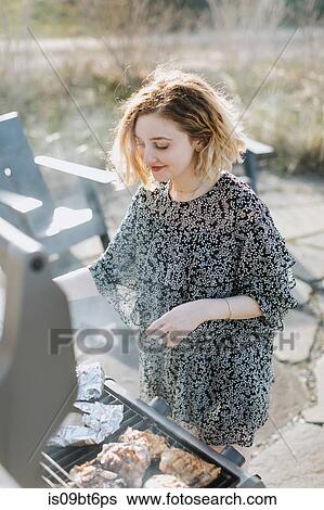 Stock Photograph - Young woman cooking on barbecue, Menemsha, Martha's Vineyard, Massachusetts, USA. Fotosearch